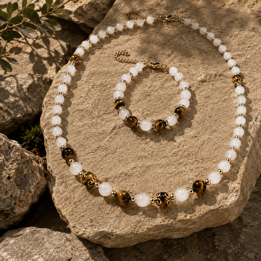 Matching tiger's eye and moonstone necklace and bracelet set displayed on a rock