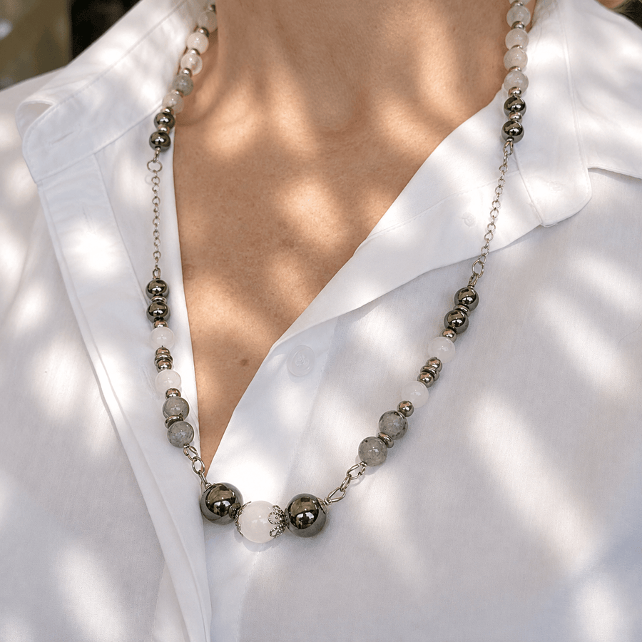 Woman wearing a beaded necklace with a white shirt, dappled sunlight